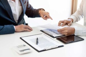 A driver reviews auto insurance documents beside car keys and a calculator at a kitchen table.